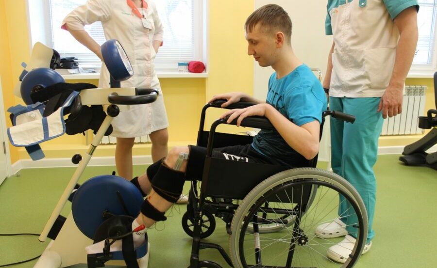 Юноша с церебральным параличом выполняет упражнения для поддержания физической формы